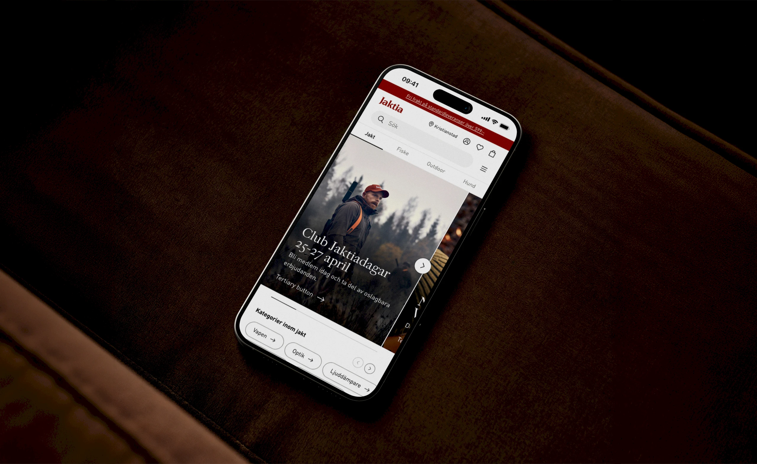 The Jaktia shop shown on a phone, lying on a brown leather couch